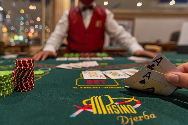 Table de jeu du Casino de Djerba, tapis vert, jetons et deux as servis par un croupier